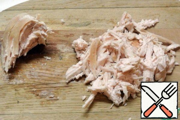 Season the chicken fillet with salt and pepper and bake in the oven. Allow to cool. Disassemble it into fibers.