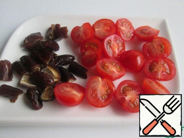 Remove the seeds from the dates and cut them into four parts.
Cut the cherry tomatoes in half.