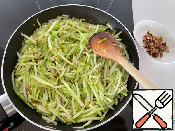 We put half of the almonds on a plate. Add the zucchini to the rest of the almonds in the pan and fry, stirring, without reducing the heat, for 5 minutes.