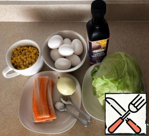 We cook chicken eggs in the way that you usually use.
Since the Iceberg lettuce leaves are laid in a kind of" head", it is easier to cut it in half, and then crumble into smaller pieces. If desired, you can also chop it with your hands, since the leaves are quite tender.
Cut the crab sticks and finely chop the onion. With canned corn, we drain the broth, which we will not need. We clean the cooled boiled eggs from the shell and crumble them.Note: since I have an electric stove, my cooking method is to bring water with eggs to a boil, followed by turning off the heating. I leave the eggs to cook in slowly cooling water for 9 minutes, which is quite enough for their complete cooking. Then I cool it in cold water, periodically changing it.