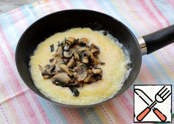 As soon as the edges of the omelet are gripped, lay out the mushrooms, cook over low heat, lifting around the edge with a spatula or fork.
