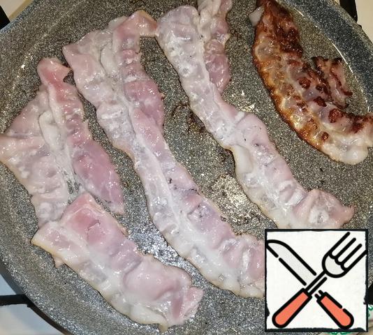 In another well-heated frying pan, fry the bacon.