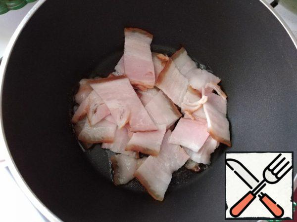 Slices of bacon are cut into pieces about 2.5 cm wide and sent to a saucepan to melt.