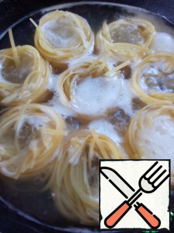 Pour boiled water into a frying pan, bring to a boil, add salt. Dip the "nest" pasta into boiling water for 1-2 minutes, holding them with forks on both sides so as not to damage the mold. Grease the heat-resistant mold with vegetable oil, put the previously extracted from boiling water and inverted "nests" into it.