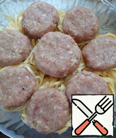 Mix the minced meat with 2 eggs and chopped onions, add salt, pepper, mix and form cutlets. Lay them on top of the pasta "nests", flatten them so that flat surfaces turn out on top.