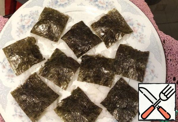 While the rice is cooling down a little
, We cut the nori leaf into small squares and spread it on the rice.Nori can be safely replaced with seaweed.If it is from the refrigerator, then we immediately put it on rice - let it warm up!