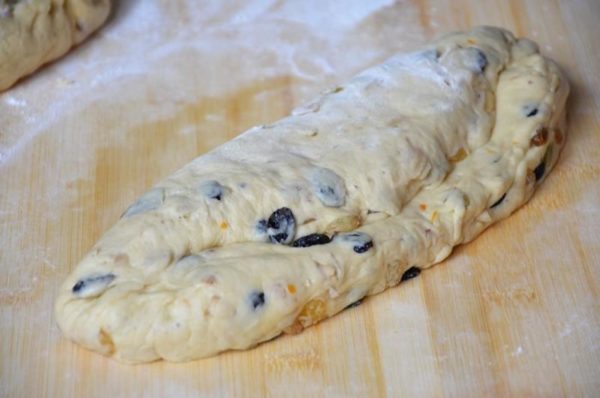 Using the palm of your hand, create an oblong depression on the dough, starting a third from the edge. Fold the smaller part of the dough into the larger one along the depression, forming the stollen.


