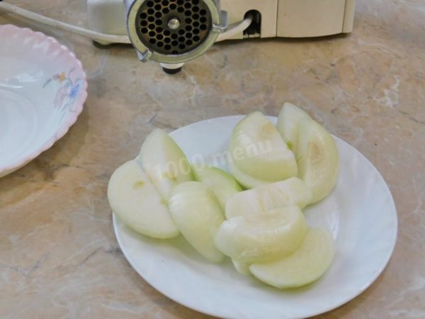 Peel and rinse the onion in cold water. To prevent eye irritation while slicing the onion, wash both the onion and the knife with cold water. Cut the onion into pieces suitable for the meat grinder. Process the peeled onion through the meat grinder and add it to the minced meat in the bowl.


