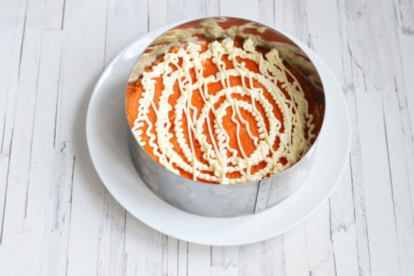 Add the grated carrots in the next layer and cover with mayonnaise. If including pickled onions, place them in the layer after the carrots.



