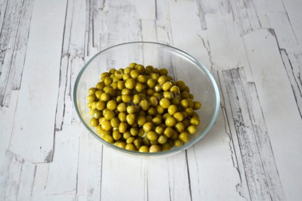 Drain the liquid from the green peas jar, placing the peas in a colander and allowing them to rest for a while. This step ensures the salad won't become watery; we want to eliminate excess moisture.


