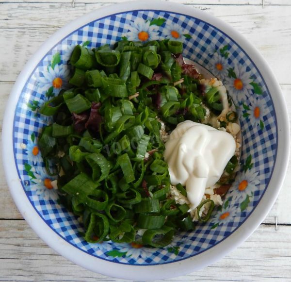Combine the chopped eggs, cheese, and onions in a deep bowl. Add mayonnaise and sour cream, thoroughly mixing to achieve a homogeneous filling.

