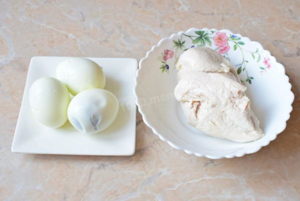 To assemble the salad, pre-cook the chicken fillet and eggs. Boil the chicken meat in salted boiling water for 25-30 minutes. Simultaneously, boil the eggs in boiling water for 7-8 minutes. Drain the hot water from the eggs and transfer them to cold water to cool. Allow both the boiled chicken meat and eggs to cool.


