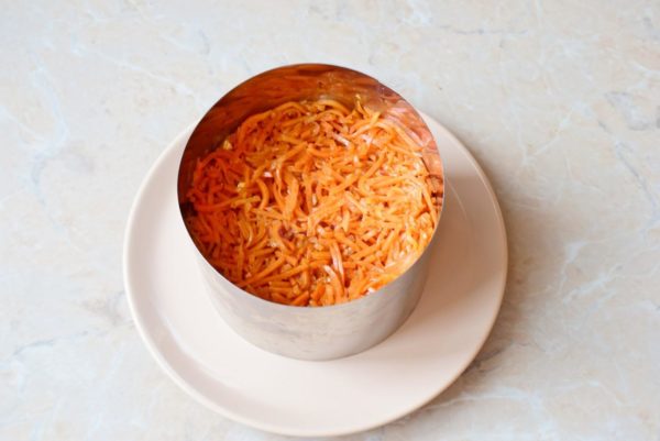 Cut the Korean carrots into slightly smaller pieces and add the next layer within the ring. Smear mayonnaise over the carrots.


