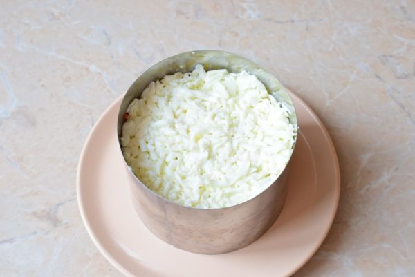 The final layer consists of grated eggs. You can grate the entire egg or, if preferred, separate the whites and yolks. Begin by arranging the grated egg whites.


