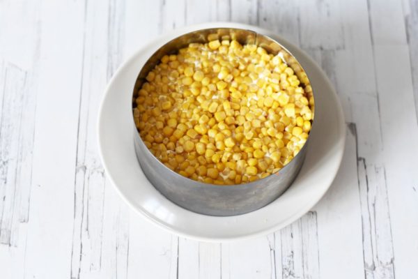 Spread canned corn on the carrots, lightly pressing into the previous layer for stability. Mayonnaise is optional for this layer.


