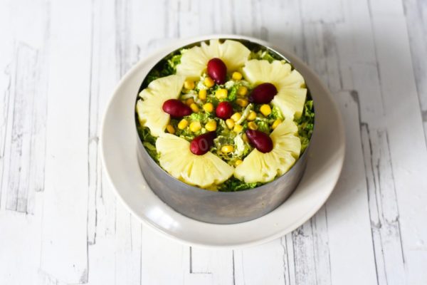 Decorate the finished salad with pineapples, corn kernels, fresh herbs, and vibrant berries. Refrigerate for 1 hour. Carefully remove the cooking ring before serving. Enjoy your meal!
