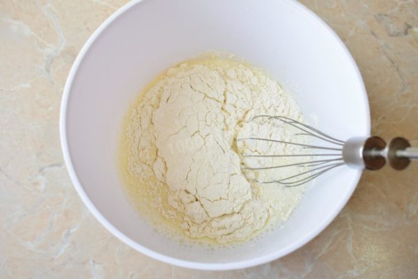 Pour milk into the bowl with the eggs and gradually add the flour and baking soda, kneading the dough.



