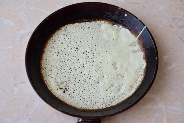 Heat a pancake pan to a hot state for frying, applying a thin layer of vegetable oil using a napkin or brush. The pan should be well-heated. Quickly pour a thin layer of dough onto it, as these thin pancakes cook rapidly. Fry the pancakes on both sides until they achieve a golden brown color.


