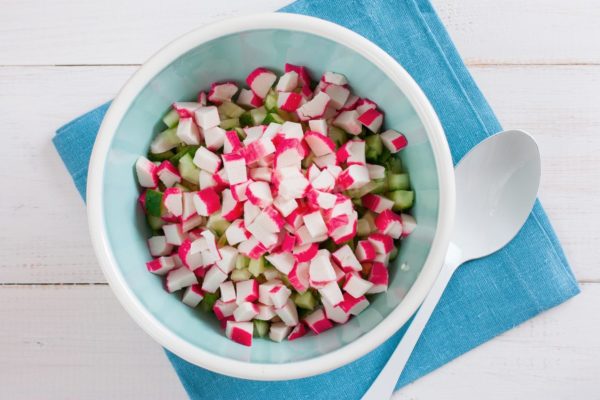 If you're using frozen crab sticks, defrost them first. Place the crab sticks, still in their packaging, on a cutting board to thaw. Once thawed, remove the cellophane wrapper. If it doesn't come off easily, you can briefly hold the sticks over steam for 1-3 seconds to make it easier to remove. Cut the crab sticks into small cubes, aiming for uniformity in the size of all the salad ingredients. Add the cubed crab sticks to the salad bowl.


