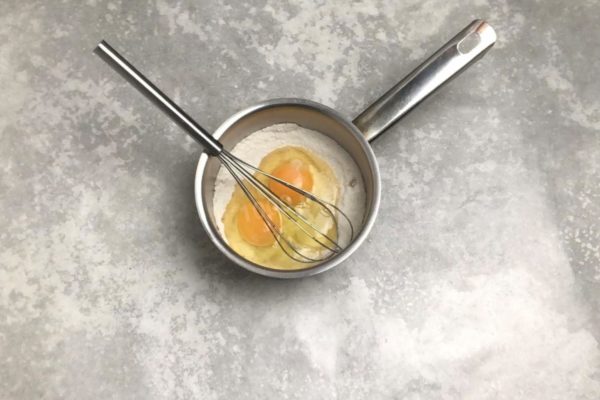 Select a saucepan with a thick bottom. This is crucial because the custard base contains eggs, which can easily overcook and curdle. A thick-bottomed saucepan ensures even and gradual heating, reducing the risk of burning. Combine granulated sugar, vanilla, and flour in the saucepan, then mix these dry ingredients together. Crack the eggs into the mixture.

