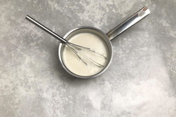 Slowly and continuously pour in the milk while stirring steadily.

