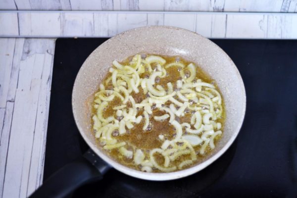 Heat butter and vegetable oil in the now-empty pan. Sauté the onion until it turns golden brown, stirring continuously.


