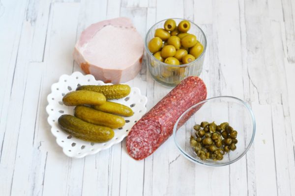 While the meat is cooking, prepare the other ingredients. You can substitute ham with other meats like pork neck, boiled sausage, or carbonade. I'm using smoked sausage, but you can also use boiled smoked sausage. Optionally, you can omit the capers altogether.


