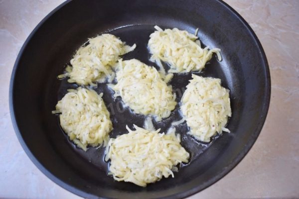 Preparing the Pan: Heat the frying pan until it's hot and then add a bit of vegetable oil. Use a tablespoon to scoop portions of the potato mixture into the pan, shaping them into oval pancakes.


