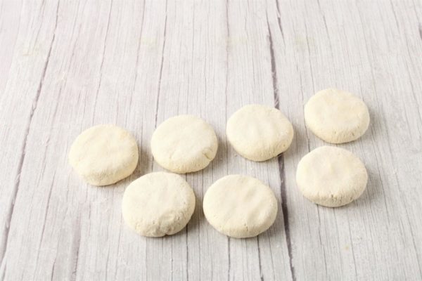 Shape each portion of dough into a bun, then flatten it into a round pancake of medium thickness. If the dough sticks to your hands, lightly dust them with flour.

