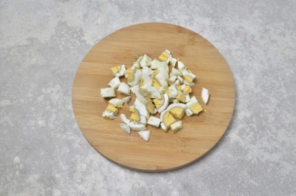 To prepare hard-boiled eggs, place them in cold water and heat them over low heat to prevent cracking. Boil the eggs for approximately 9 minutes after the water reaches a boil. Then, transfer the eggs to cold water and let them cool. This will make it easier to peel the eggs. Cut the peeled eggs into pieces of uniform size, similar to the cucumber pieces.

