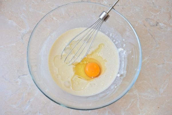 To the yeast mixture, add salt, vegetable oil, and one egg. Combine all the ingredients, using a whisk or spoon.

