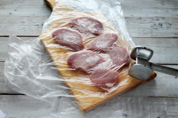 Thoroughly wash the meat under running water and pat it dry using paper towels. If needed, remove any tendons or membranes with a knife. Slice the meat into thin, wide pieces, approximately 1 cm thick, cutting across the grain. Place the meat on a cutting board, covering it with plastic wrap or cling film. This will prevent meat juice from splattering during pounding. Use a kitchen mallet to tenderize each piece on both sides.


