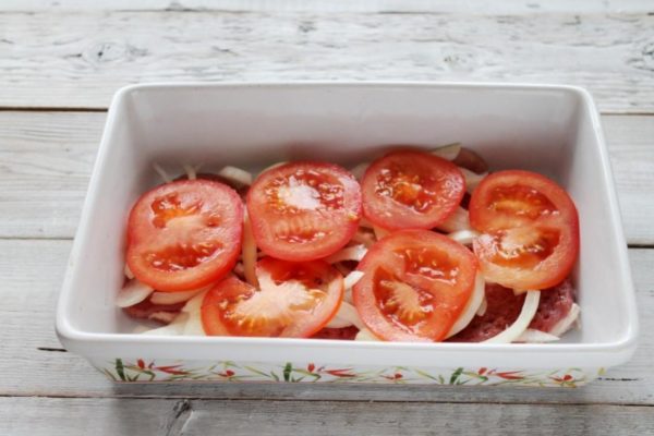 Wash and dry the tomatoes with paper towels, and remove the stems if necessary. Using a sharp knife, slice the tomatoes into thin rings. Arrange them on top of the onion layer. While fresh vegetables can be replaced with tomato sauce or omitted, including them will enhance the dish's flavor and juiciness.


