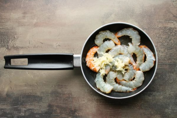Once the shrimp begin to turn red, add the crushed garlic to the pan. Mix everything thoroughly.


