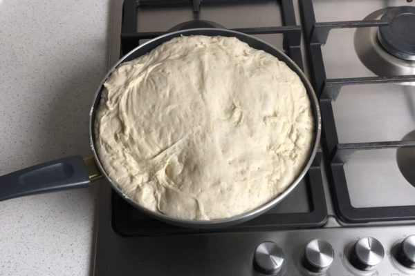The dough will rise again. Turn the stove to the lowest possible heat setting. Place the pan on the stove and cover it with a lid. Fry the bread for about half an hour, being careful not to let it burn. If you have a transparent lid, avoid lifting it too often to ensure the bread rises well.


