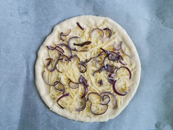 Divide the toppings evenly between the two pizzas. Start with half of the cheese, followed by the sautéed onion.


