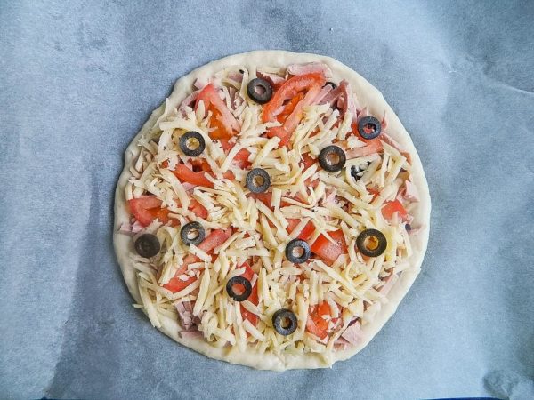 Sprinkle the remaining cheese evenly and add the olives as the final topping. Bake for 15-20 minutes on a middle oven rack at 200 degrees Celsius (392 degrees Fahrenheit) using both top and bottom heating elements. Cooking times may vary depending on your oven, so check for readiness. In a finished pizza, the dough will rise and turn slightly golden. When gently pressed with the palm of your hand, the dough should not give. Enjoy your homemade pizza!
