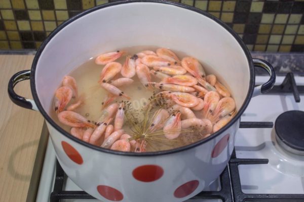 Once the water with spices is boiling, carefully place the prepared shrimp into the saucepan and bring it back to a boil.

