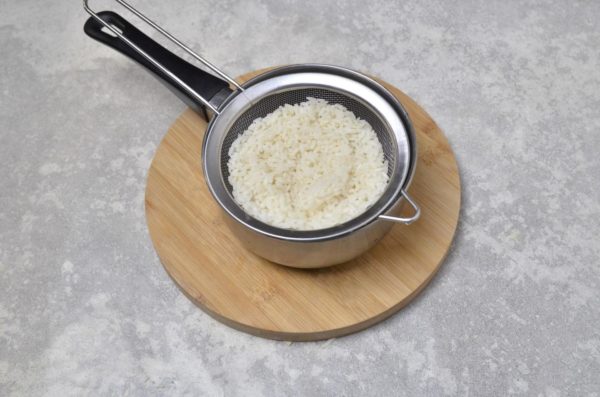 Start by cooking the rice. Rinse the rice thoroughly, then place it in a pot of clean, cold water. Bring the water to a boil and cook the rice for a couple of minutes. Drain the rice using a sieve and let it cool.


