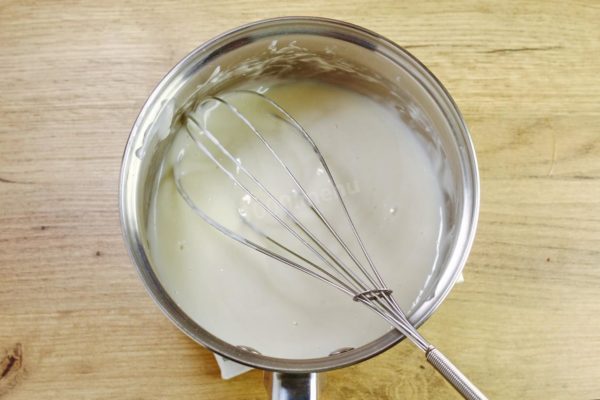Place the saucepan over medium heat and bring the mixture to a boil while stirring constantly. Reduce the heat slightly and cook until the mixture thickens. Keep stirring throughout the process. If you want a thicker mayonnaise, you can cook it for a bit longer. Keep in mind that the consistency of the flour mixture will become thicker as it cools. Let it cool to room temperature.

