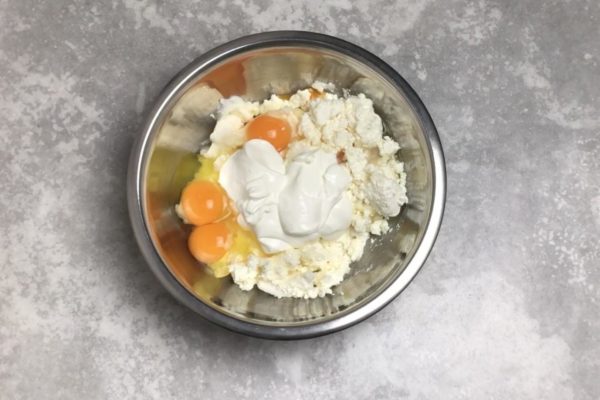 Crack the eggs into the cottage cheese. Use larger eggs, or increase their quantity if using smaller ones. Eggs contribute to the casserole's fluffiness, so don't reduce them. If you don't have a blender, beat the eggs with sugar separately, then add them to the main mixture. Incorporate sour cream, considering the moisture level of your cottage cheese (wet or dry).
