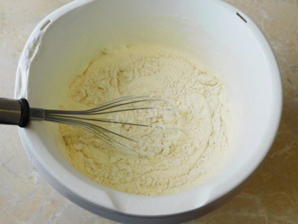 Begin adding the sifted flour mixture to the beaten eggs in small portions. Gently fold it into the batter using a whisk, aiming to retain as much of the air bubbles in the eggs as possible. Be cautious not to overmix, as this can cause the batter to deflate. Adjust the amount of flour as needed to achieve a moderately liquid sour cream-like consistency.


