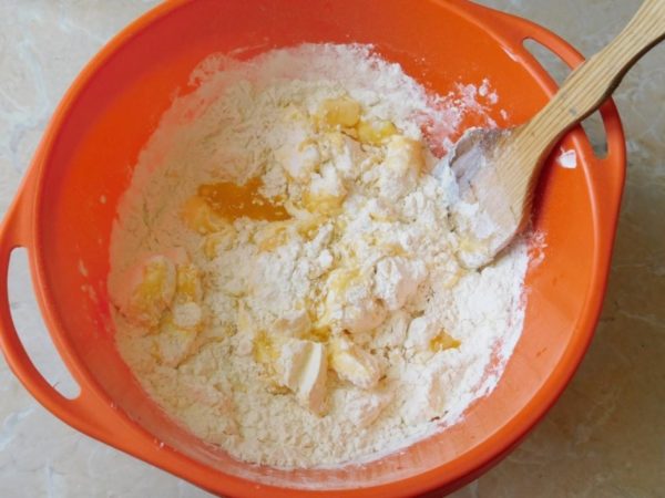 In your mixing bowl, break the softened butter into pieces using a fork, and then add baking soda and gradually incorporate the flour. Initially, you can mix the dough with a wooden spatula.

