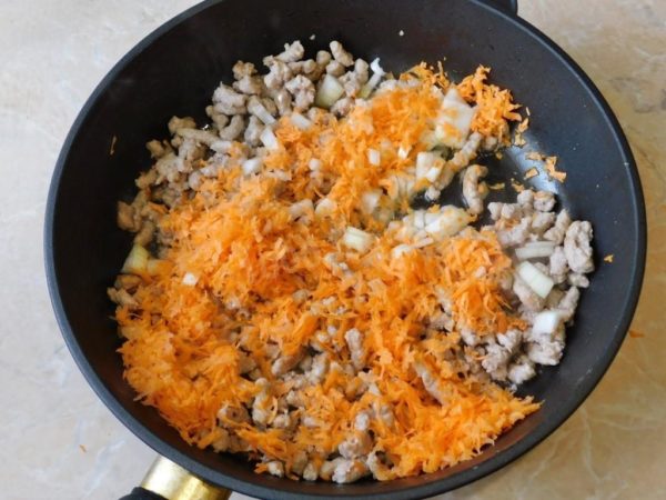 Add the diced onions and grated carrots to the skillet with the browned ground meat. Sauté the mixture together for an additional 2-3 minutes.

