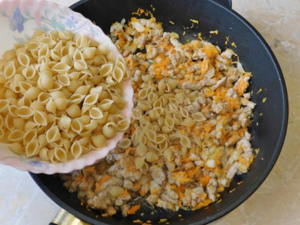 Next, add the measured pasta to the skillet and pour in hot water. Season with a pinch of salt and your preferred spices. Stir well and bring it to a boil. Then cover the skillet with a lid and reduce the heat. Let it all simmer for 12-15 minutes until the pasta is cooked. If the water evaporates before the pasta is done and it's still slightly moist, you can add a small amount of hot water to reach the desired consistency.

