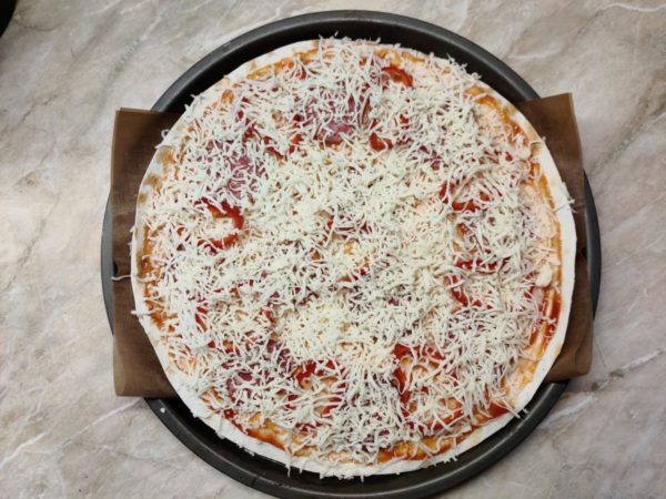 Grate the remaining two-thirds of the cheese over the top. Bake the pizza in the preheated oven at 180 degrees Celsius for a maximum of seven minutes. Avoid baking it longer, as pita bread can become overly dry and brittle. Keep an eye on the cheese crust, and once it's browned, it's ready to be taken out. Serve the pizza hot and feel free to drizzle some barbecue sauce on top if desired. Enjoy your meal!