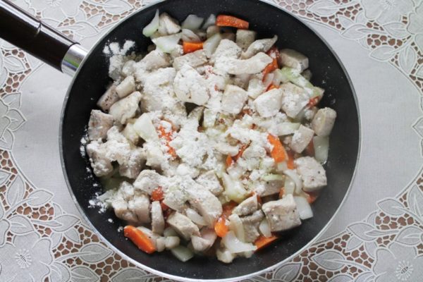 Sprinkle a thin layer of flour over the contents of the pan and immediately blend it with the meat and vegetables to ensure even distribution and prevent lumps from forming.

