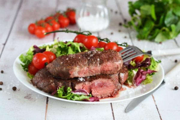 Place the finished steaks, cooked to your desired level of doneness, on a plate alongside fresh salad and vegetables, then serve them to the table. Enjoy your meal!


