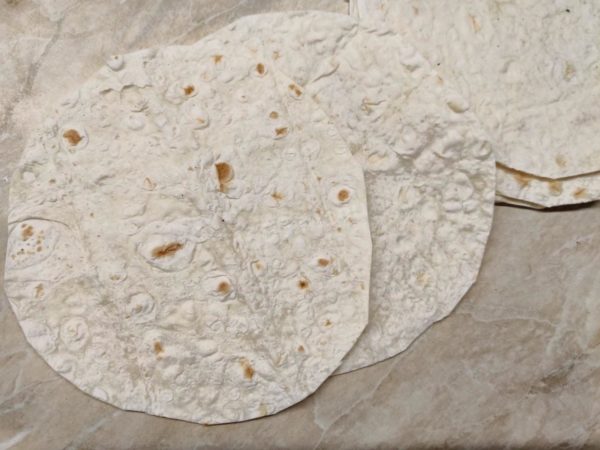 Using kitchen scissors, cut out circles from the pita bread that match the size of your frying pan, ensuring you have an even number of these pita bread rounds.

