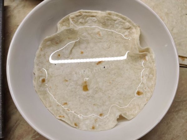 Briefly dip two pita bread circles entirely into the prepared saltwater mixture for a few seconds. The circles will adhere to each other firmly, which is what we want.

